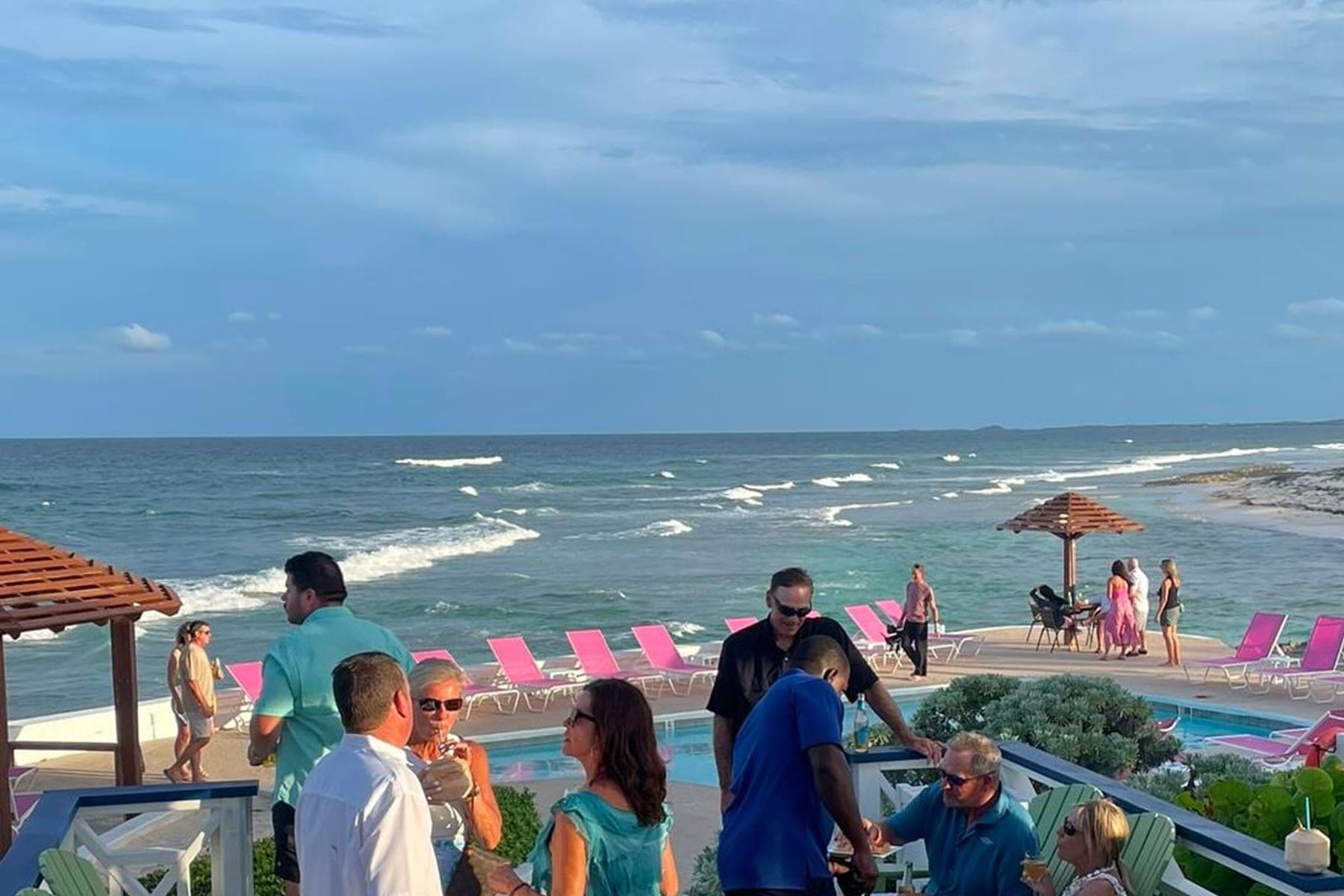 Guests with drinks on the pool deck at dusk