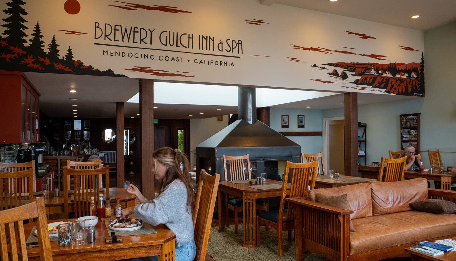 The Great Room at Brewery Gulch Inn: hand-painted coastal mural, four-sided wood-burning fireplace and breakfast tables