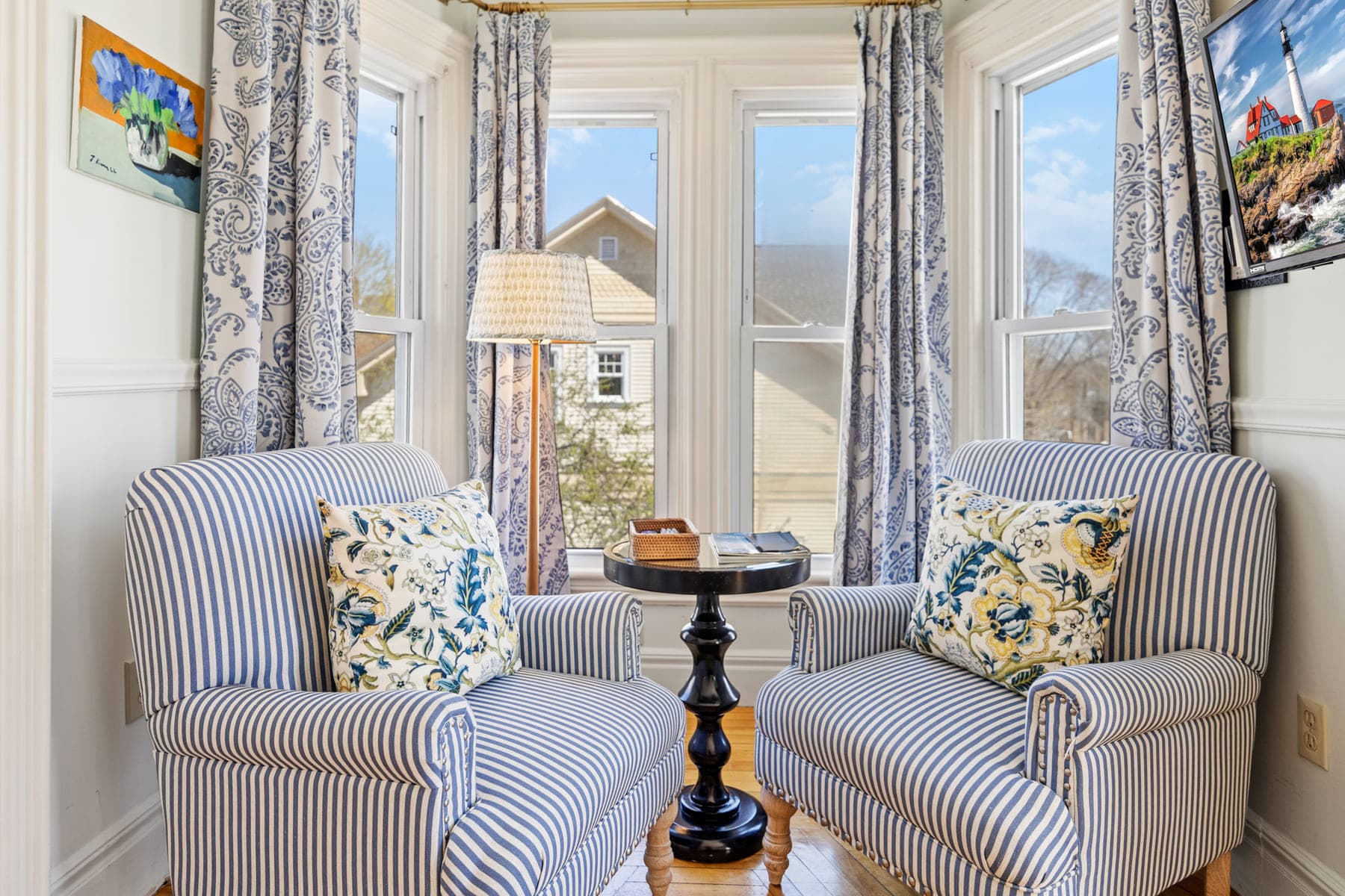 Two striped armchairs facing each other in a sunlit bay window